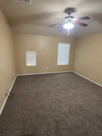 an empty room with windows and fan