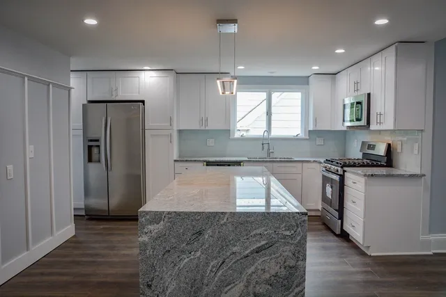 a large kitchen with stainless steel appliances granite countertop a stove a sink and a refrigerator