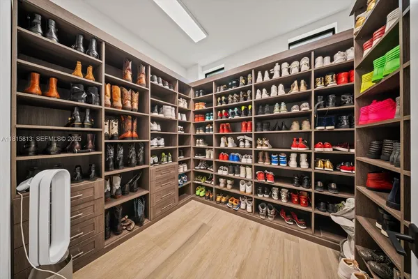 a walk in closet with wooden floor