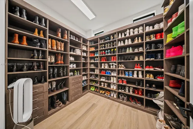 a walk in closet with wooden floor