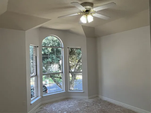 an empty room with windows and ceiling fan
