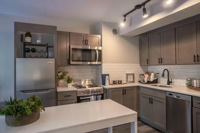 a kitchen with stainless steel appliances a sink a stove a refrigerator and cabinets