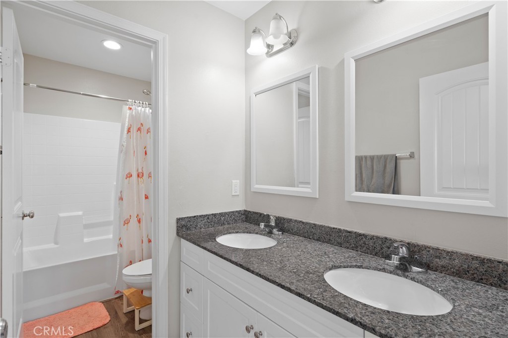 12875 Wainwright Lane Moreno Valley, CA 92555 - Photo 20 of 37 a bathroom with a granite countertop sink toilet a mirror a shower and a bathtub