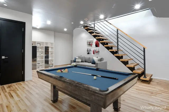a room with wooden floor pool table and stairs