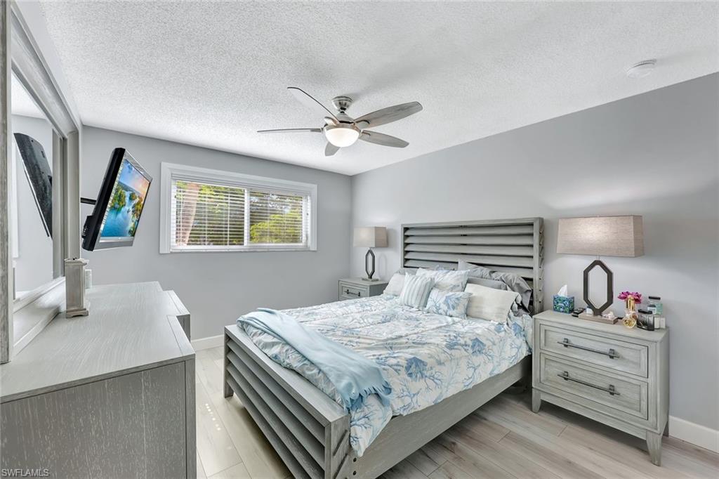 766 Central Avenue, Unit 207 Naples, FL 34102 - Photo 10 of 18 a bedroom with a large bed and a chandelier