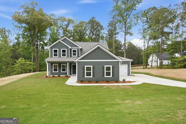 a front view of a house with a garden and trees