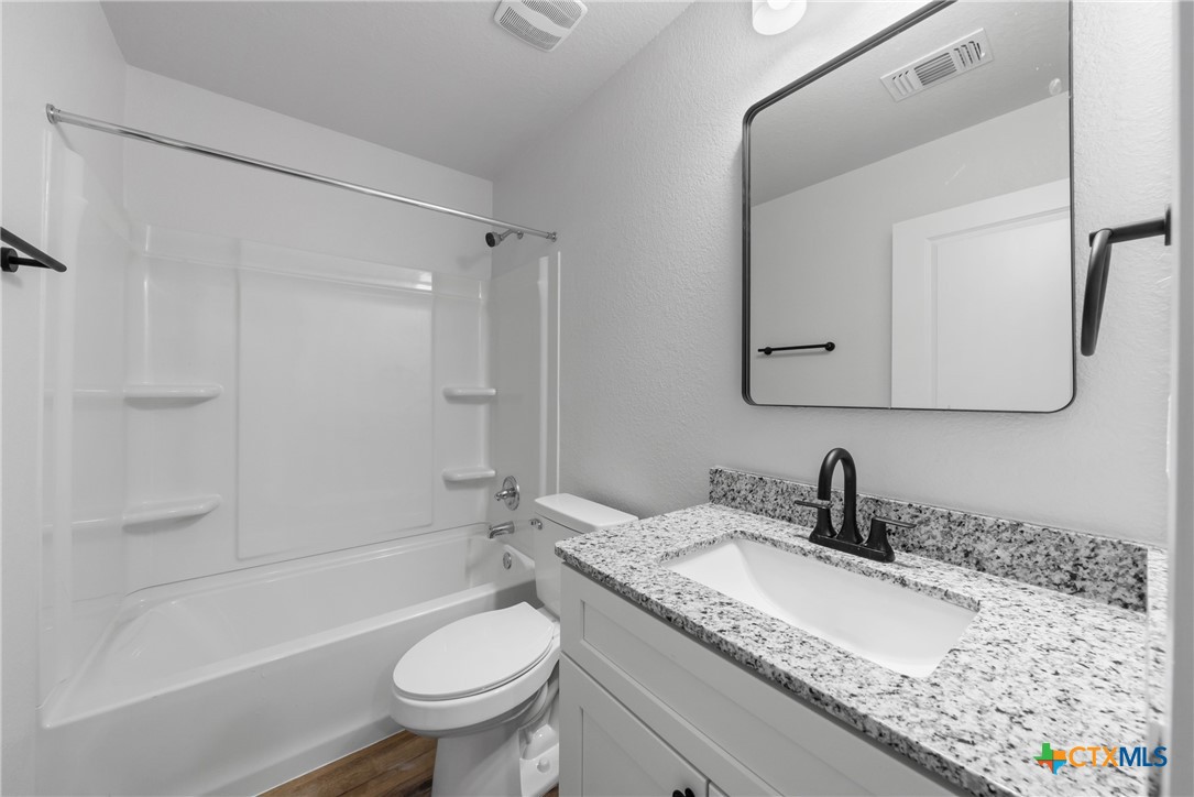 712 South 28th Street, Unit A Temple, TX 76501 - Photo 23 of 24 a bathroom with a granite countertop tub sink toilet and mirror