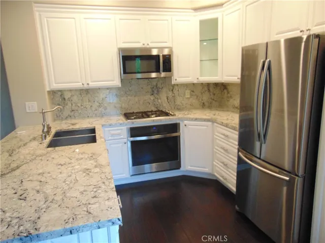 a kitchen with granite countertop a refrigerator stove and microwave