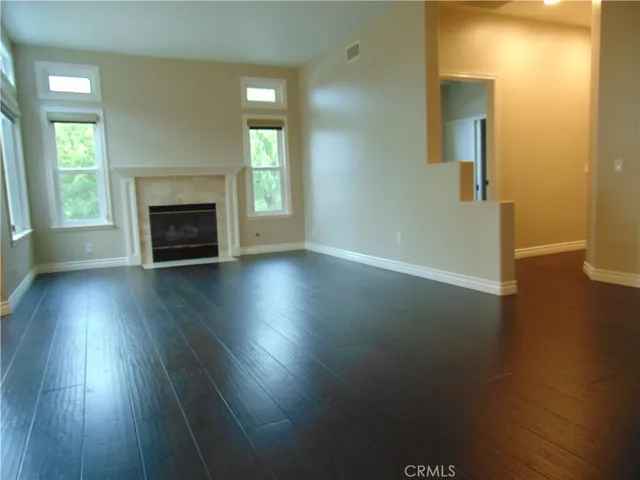 an empty room with wooden floor a fireplace and windows