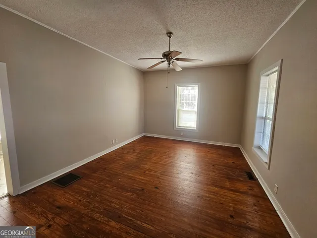 a view of empty room with wooden floor and fan