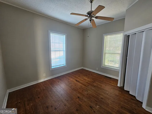 a view of an empty room with window and wooden floor