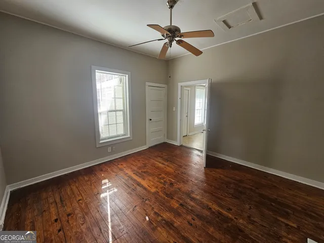 a view of an empty room with a window and wooden floor