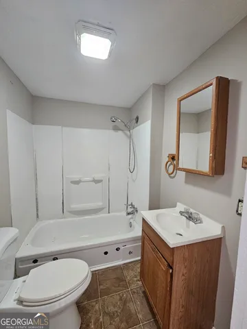 a bathroom with a bathtub shower sink mirror vanity and toilet