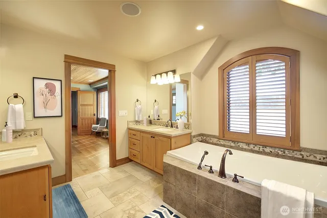 a spacious bathroom with a tub sink and mirror