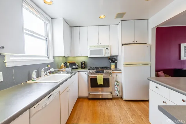 a kitchen with a sink a refrigerator a window and white cabinets