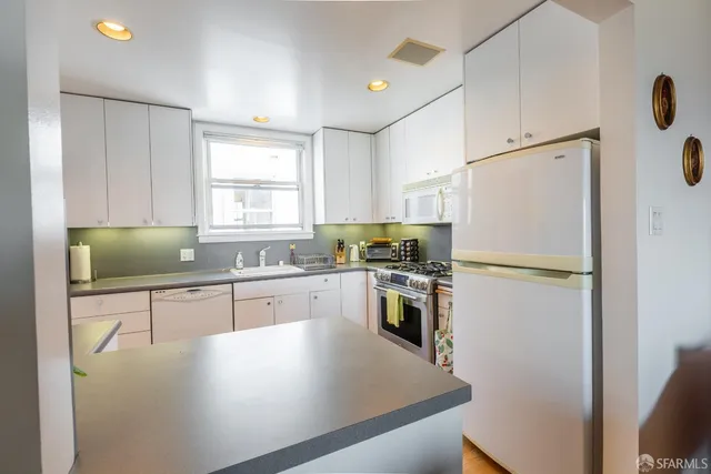 a kitchen with granite countertop a refrigerator a sink a stove a dining table and chairs