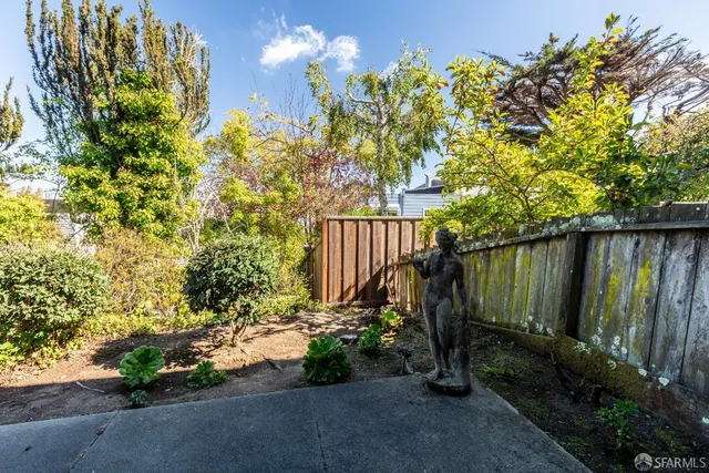 a view of backyard with potted plants and wooden fence