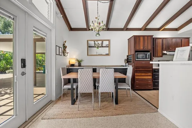 a dining room with wooden floor a chandelier a wooden table and chairs