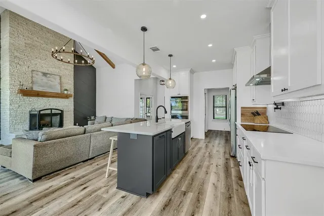 a large kitchen with stainless steel appliances kitchen island granite countertop a sink and a refrigerator