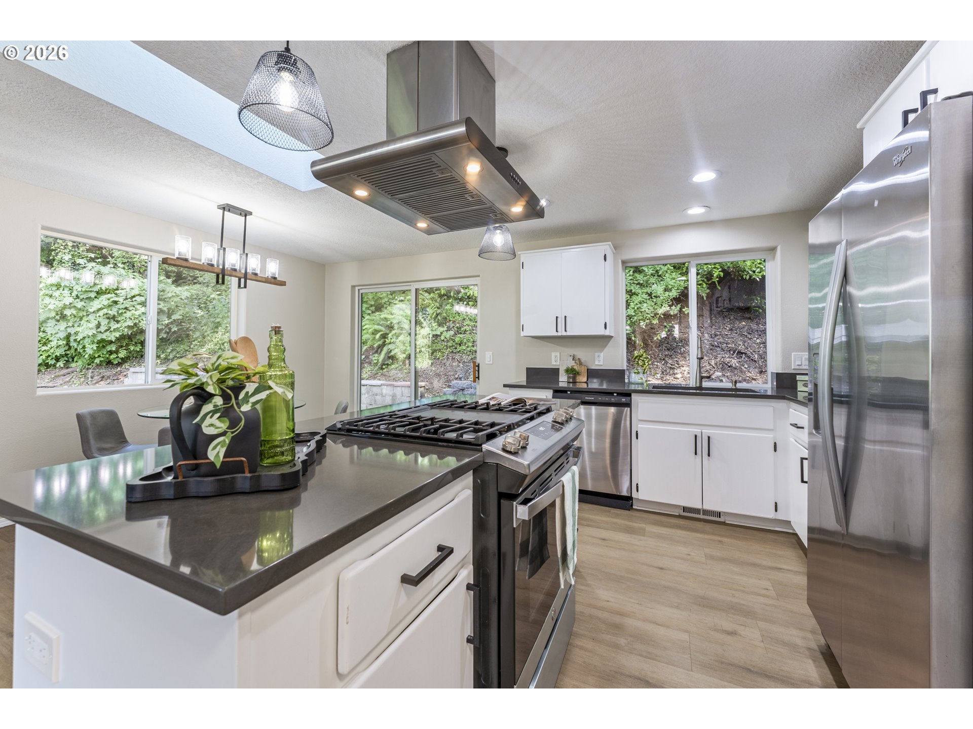 4024 Southeast 154th Place Portland, OR 97236 - Photo 4 of 43 a kitchen with stainless steel appliances granite countertop a stove a refrigerator a sink a counter space and a dining table