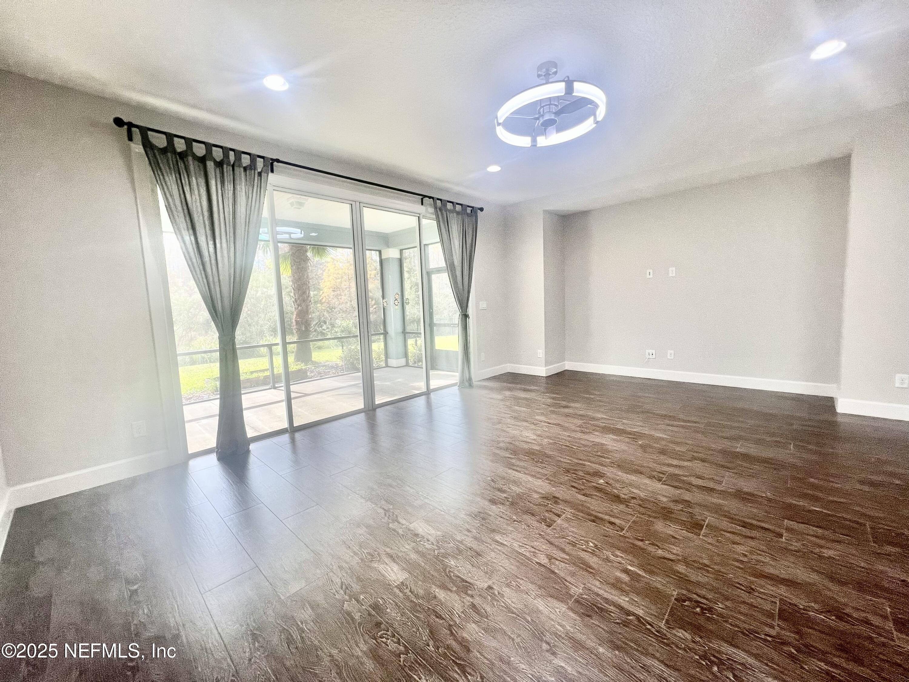 242 Orchard Lane St. Augustine, FL 32095 - Photo 13 of 44 an empty room with wooden floor and windows with curtains