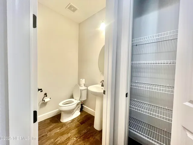 an empty room with wooden floor and windows with curtains