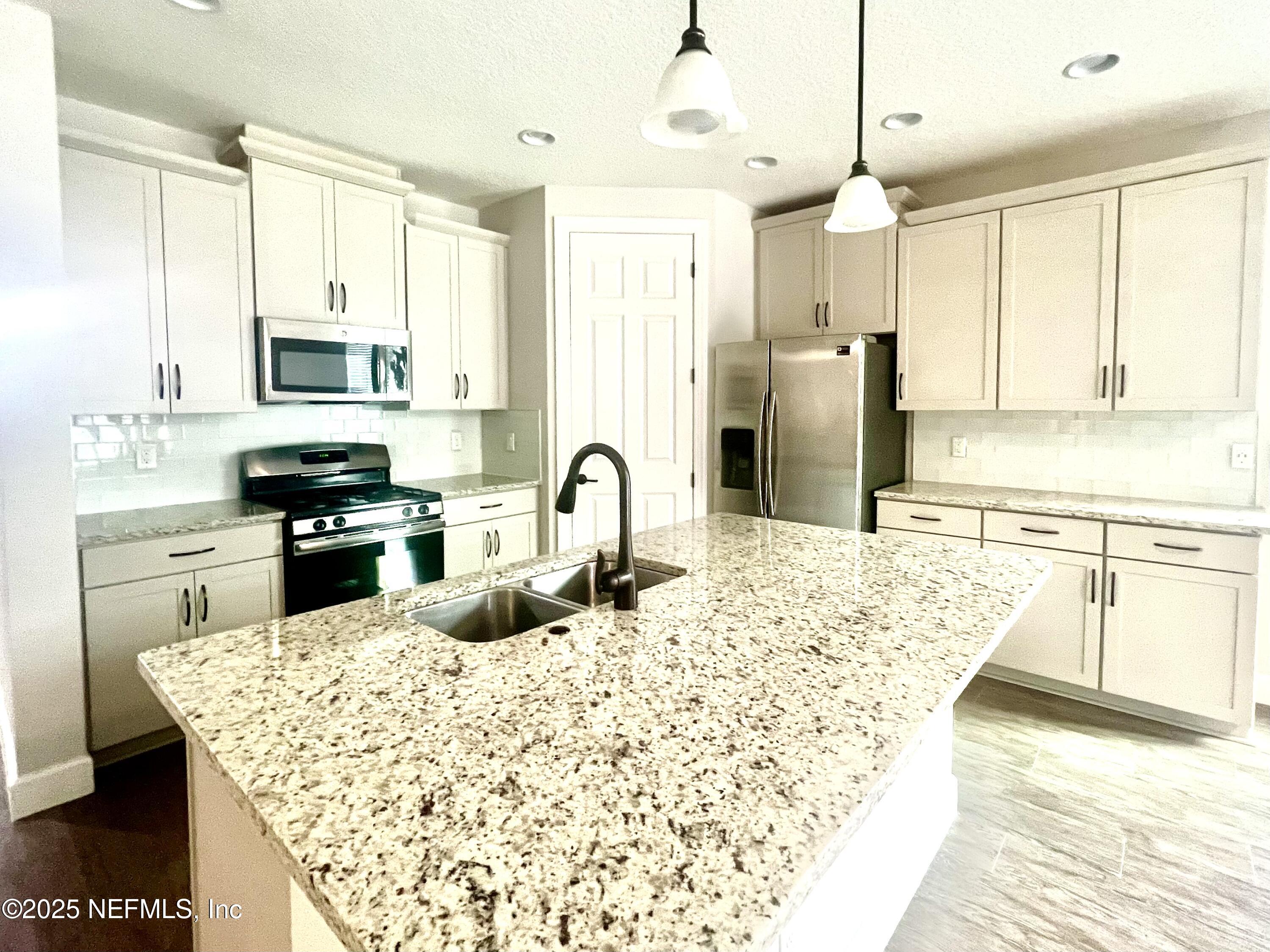 242 Orchard Lane St. Augustine, FL 32095 - Photo 10 of 44 a kitchen with stainless steel appliances kitchen island granite countertop a stove a sink and a microwave