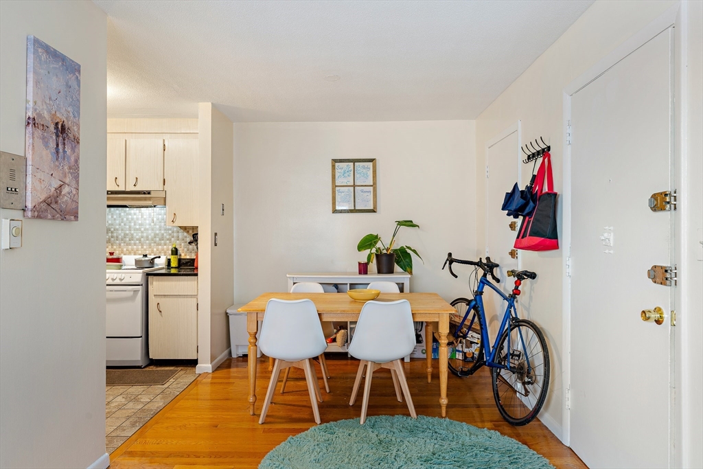 10 Scottfield Road, Unit 34 Boston, MA 02134 - Photo 2 of 19 a dining room with furniture wooden floor a rug and a chandelier