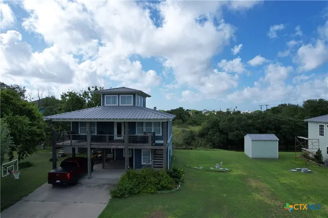 a view of a big house with a big yard plants and a barbeque