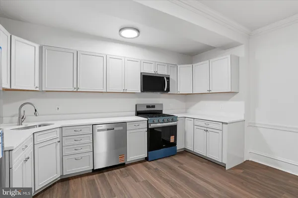 a kitchen with cabinets stainless steel appliances a sink and wooden floor