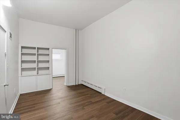 an empty room with wooden floor closet and windows