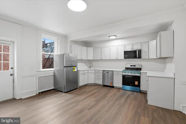 a kitchen with a refrigerator a stove top oven a sink dishwasher and white cabinets with wooden floor