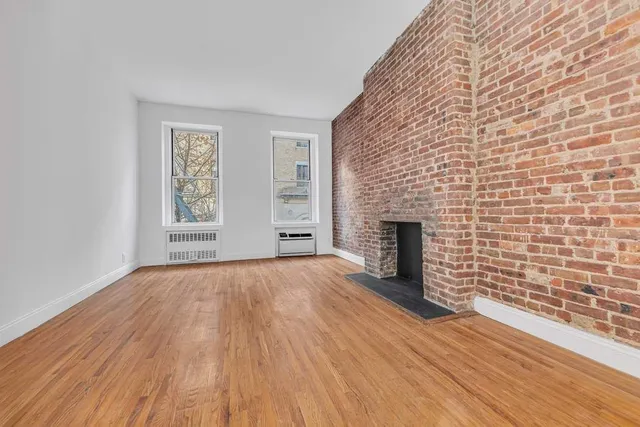a view of empty room with wooden floor and fireplace