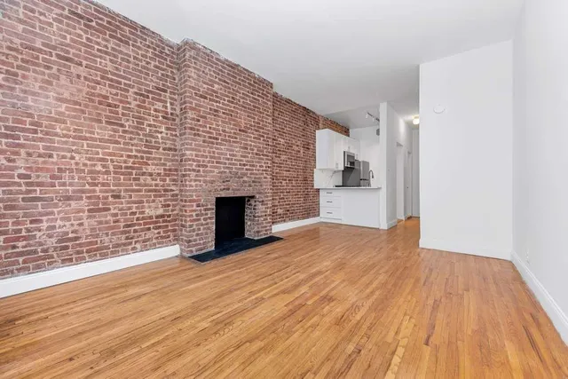 a view of empty room with wooden floor and fireplace
