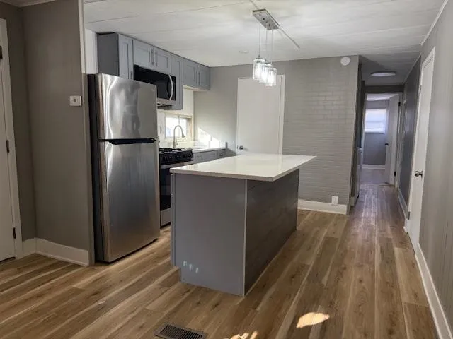 a kitchen with stainless steel appliances a refrigerator and a wooden floor