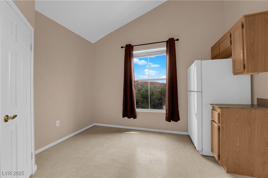 10550 West Alexander Road, Unit 2233 Las Vegas, NV 89129 - Photo 8 of 35 Kitchen with lofted ceiling, light floors, baseboards, and freestanding refrigerator