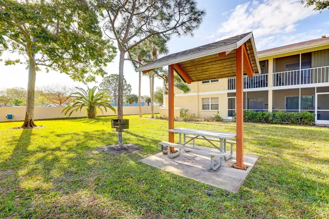 a view of swimming pool with lawn chairs and large trees