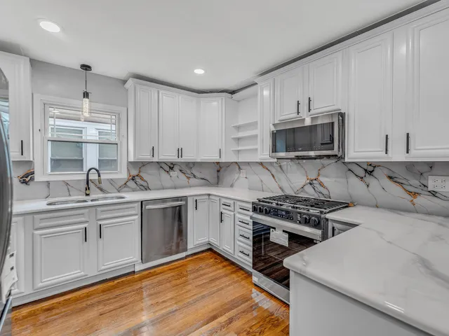 a kitchen with stainless steel appliances a sink dishwasher a stove and white cabinets