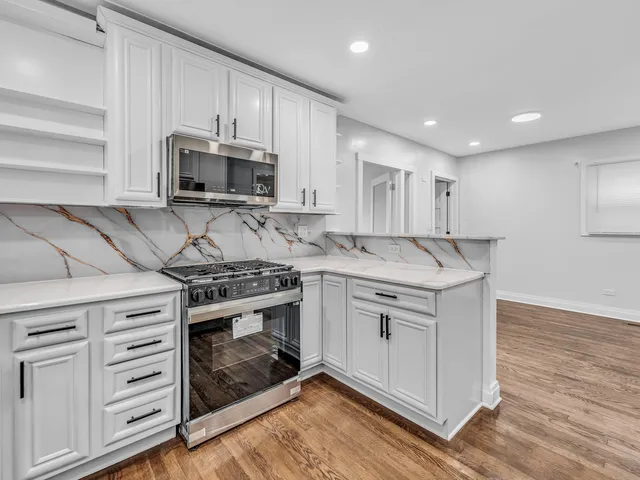 a kitchen with stainless steel appliances granite countertop a stove a sink and a microwave