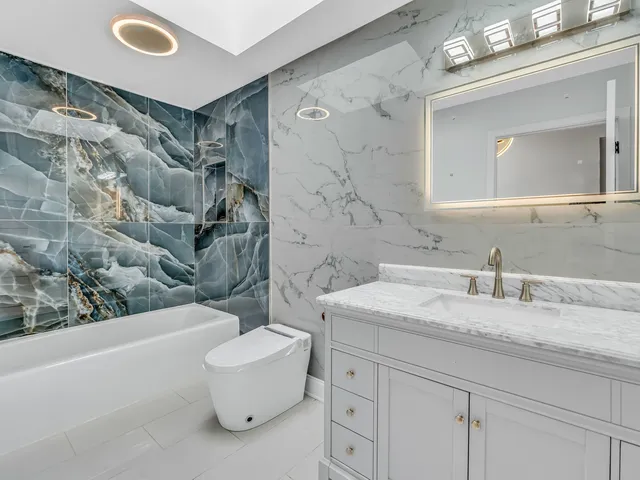a bathroom with a granite countertop sink mirror vanity and toilet