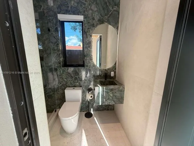 a white toilet sitting next to a shower