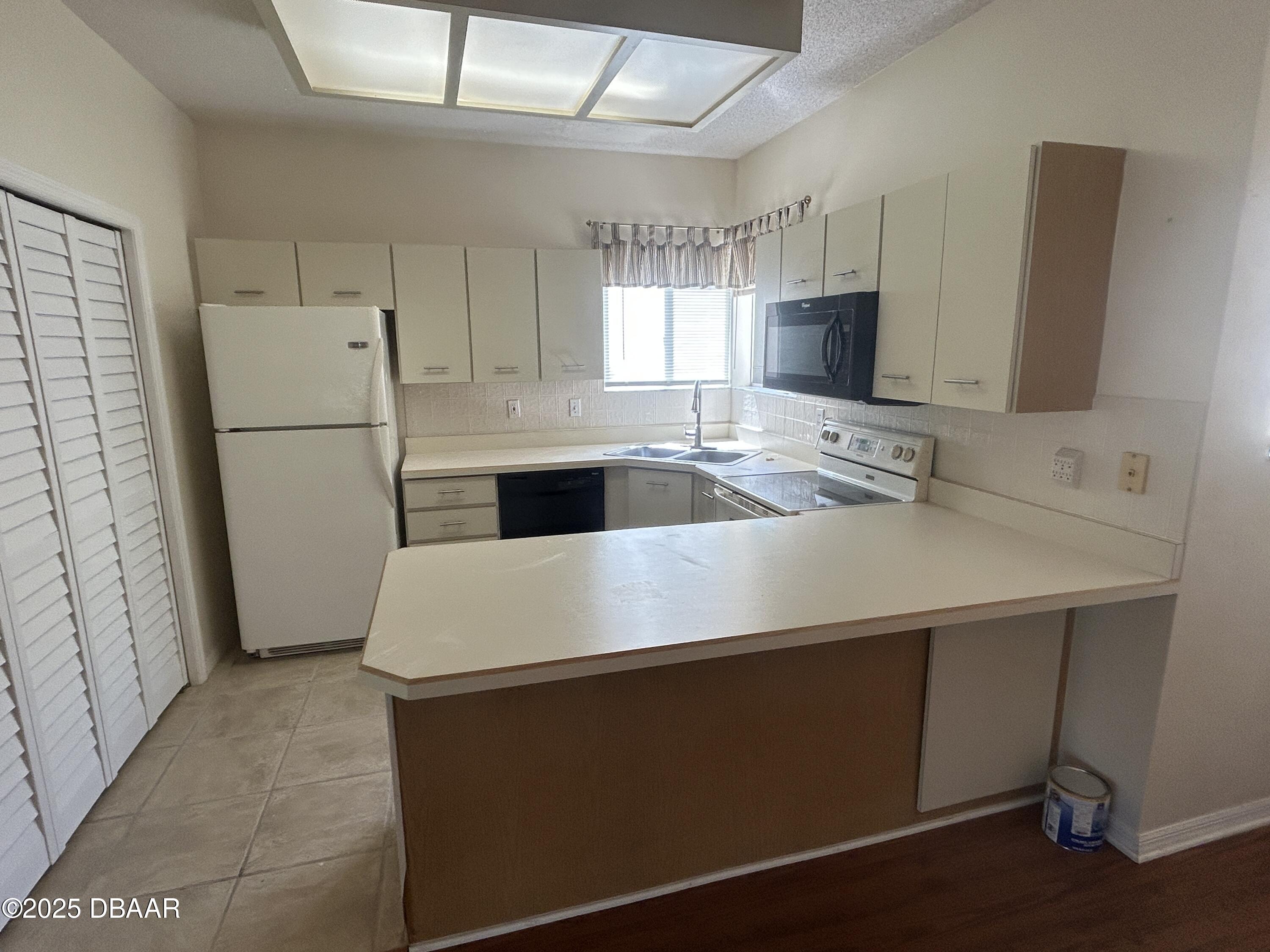 38 Magnolia Drive South, Unit S Ormond Beach, FL 32174 - Photo 3 of 12 a white kitchen with a sink a refrigerator and cabinets