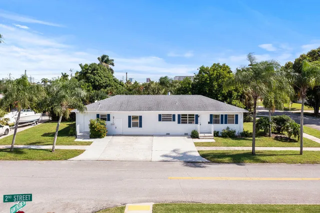 a view of a house with a big yard and large trees