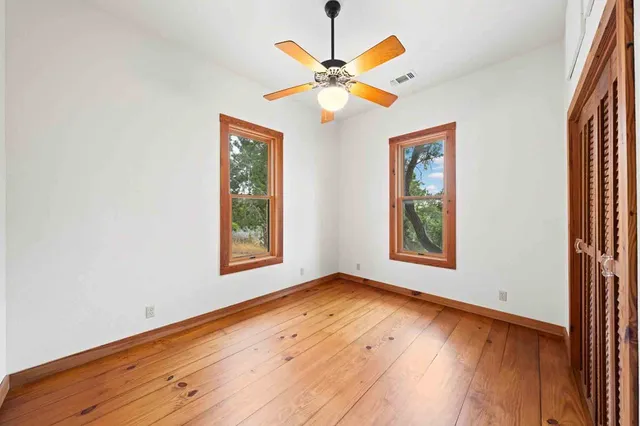 a view of empty room with wooden floor and fan