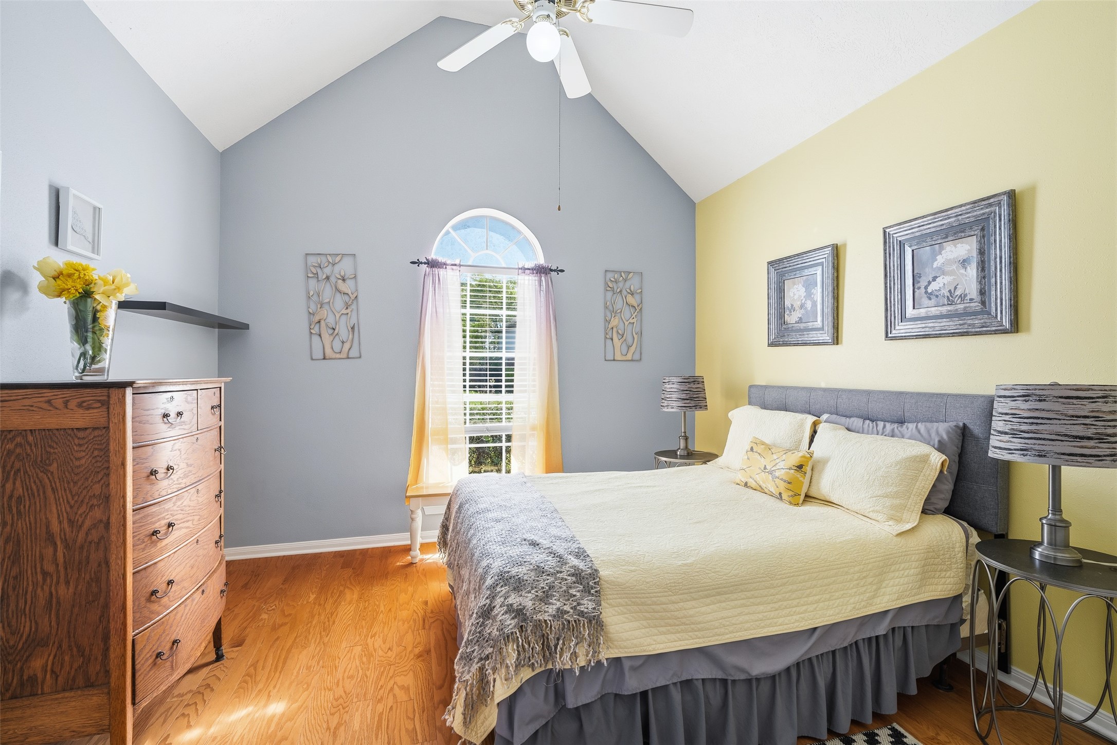 21719 Long Castle Drive Spring, TX 77388 - Photo 13 of 19 This bedroom features rich wood flooring, a ceiling fan, and a large window with privacy blinds, providing a bright and comfortable living space.