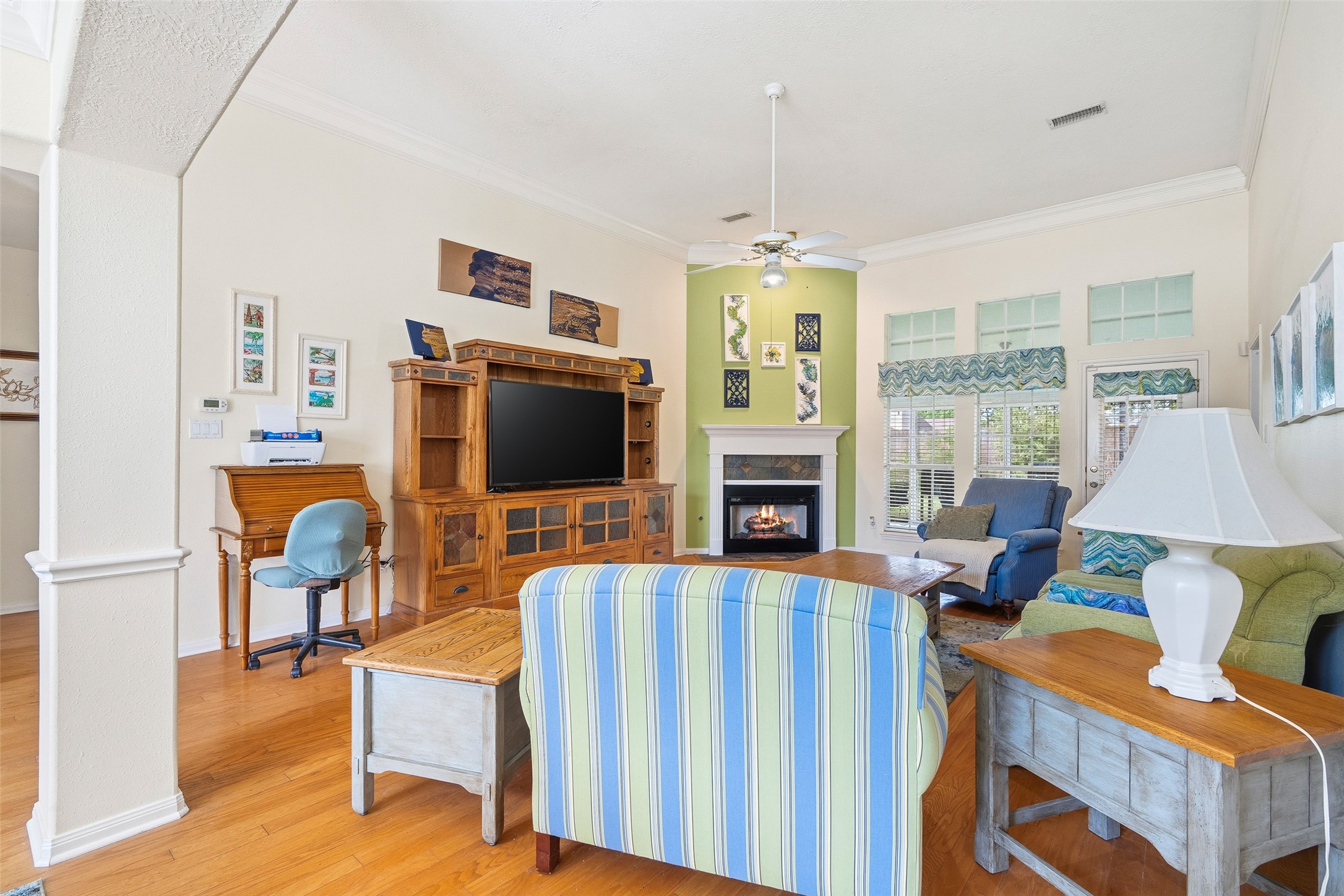 21719 Long Castle Drive Spring, TX 77388 - Photo 4 of 19 Gather in the inviting living room, showcasing a beautiful fireplace, multiple windows and a modern ceiling fan that adds a touch of sophistication — the perfect blend of comfort and timeless style.