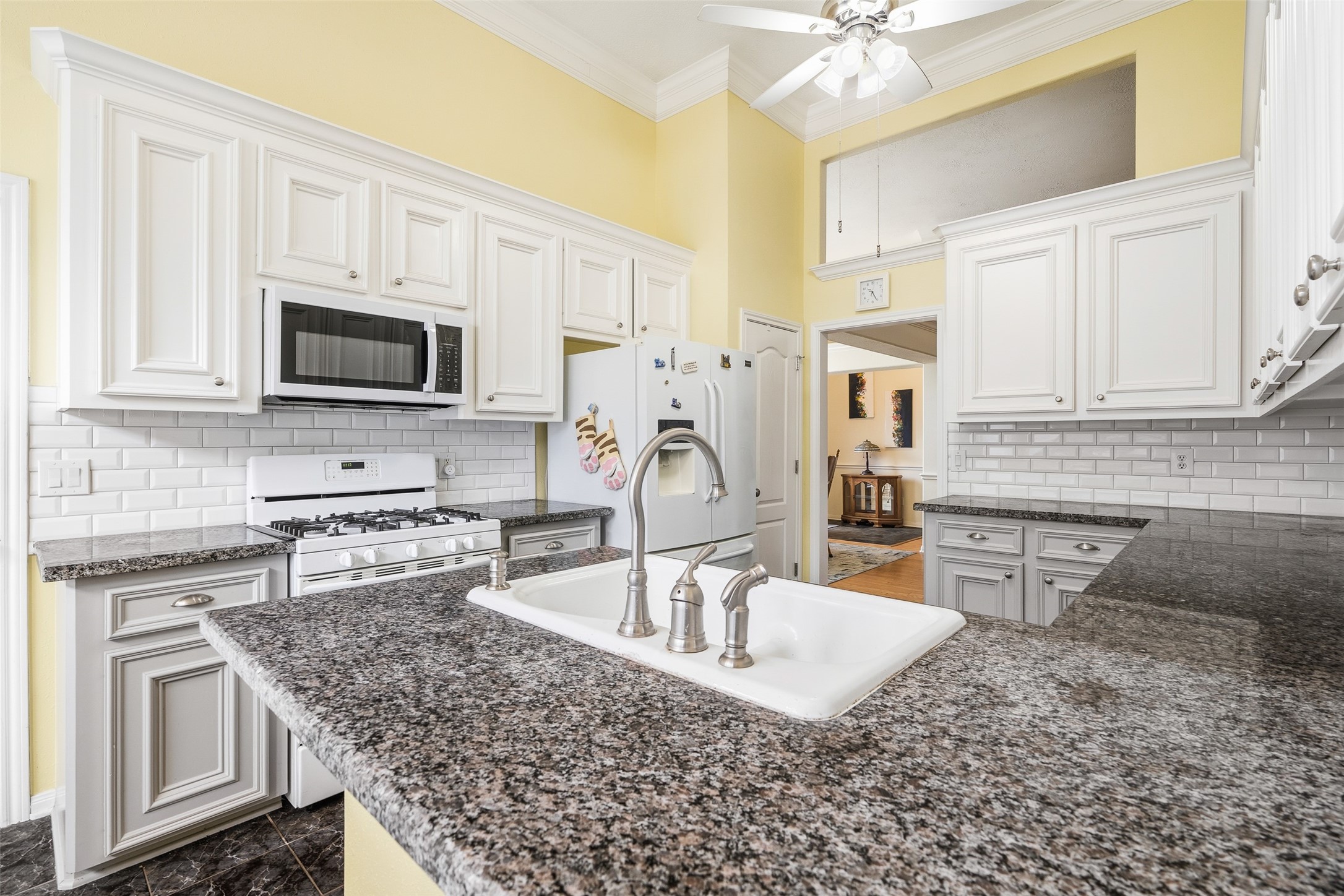 21719 Long Castle Drive Spring, TX 77388 - Photo 5 of 19 Fall in love with this beautifully designed kitchen featuring sleek double-tones cabinets, a classic white subway tile backsplash, and a spacious island—perfect for cooking, gathering, and entertaining in style.