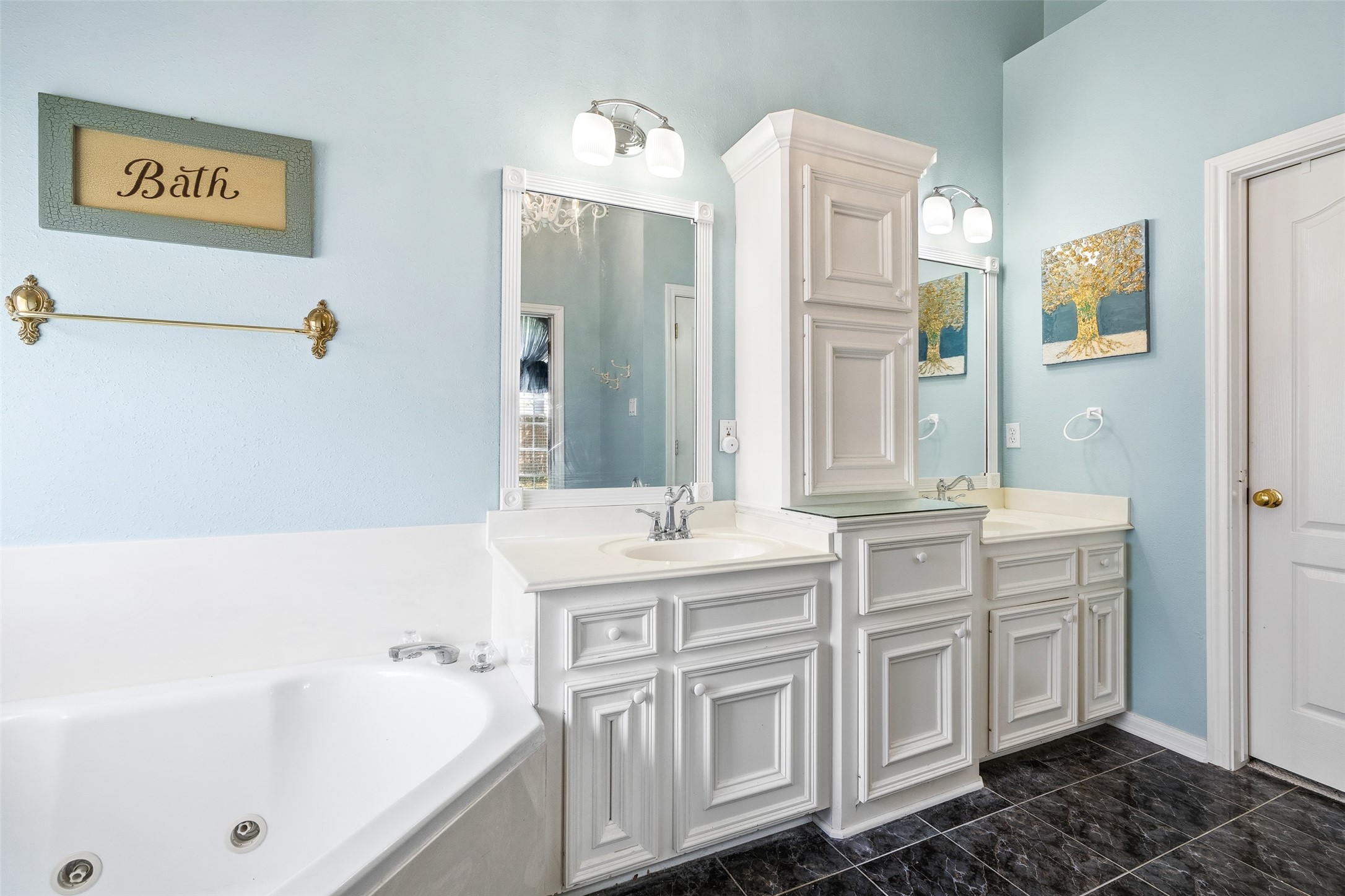 21719 Long Castle Drive Spring, TX 77388 - Photo 10 of 19 The primary bathroom also offers a double-sink vanity with white cabinets, dark tile flooring and a toilet, combining clean design with everyday functionality for a fresh, modern look.