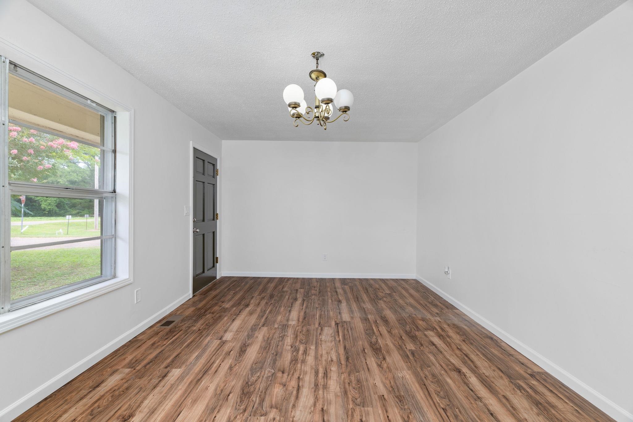 217 Red Bay Road Golden, MS 38847 - Photo 3 of 33 Spacious room featuring wood-finish flooring, crisp white walls, and a multi-bulb chandelier