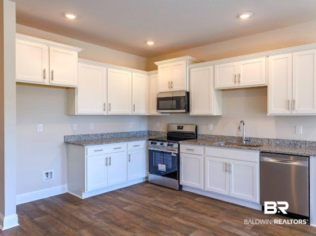 13791 Logan Place Foley, AL 36535 - Photo 8 of 25 Modern kitchen featuring white cabinetry, wood-finish flooring, recessed lighting, and stainless steel appliances including a range, microwave, and dishwasher